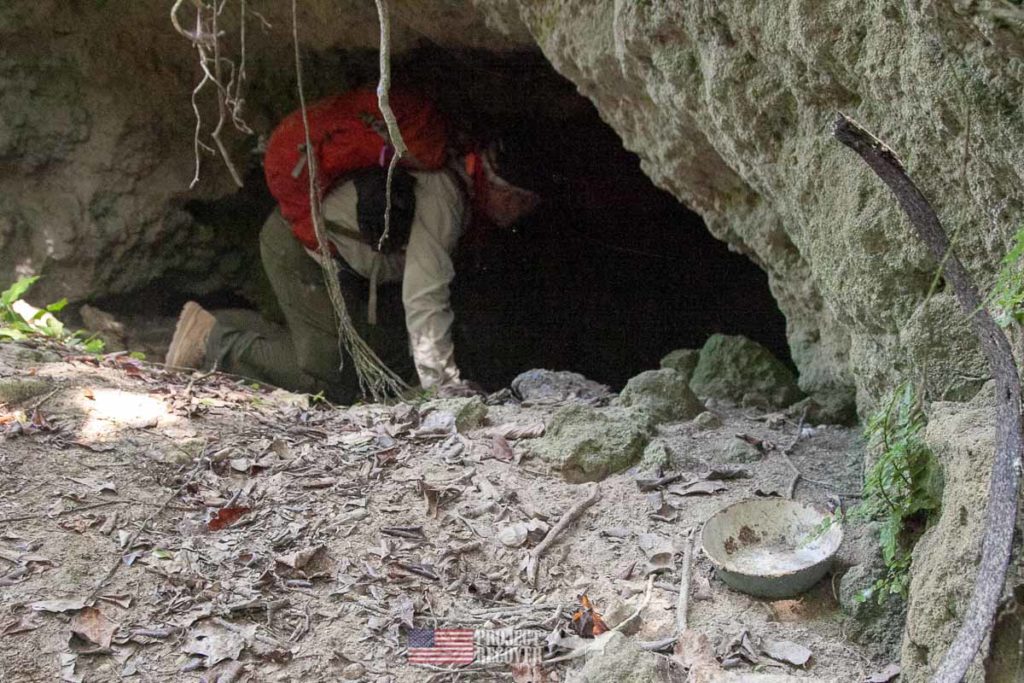 Pat Scannon, Project Recover President, kneels to enter WWII Japanese cave on Peleliu.