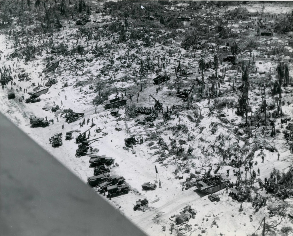 US Marines move supplies ashore across the beachhead on Peleliu in late September 1944. What appears to be water in the lower left is the wing of the airplane.