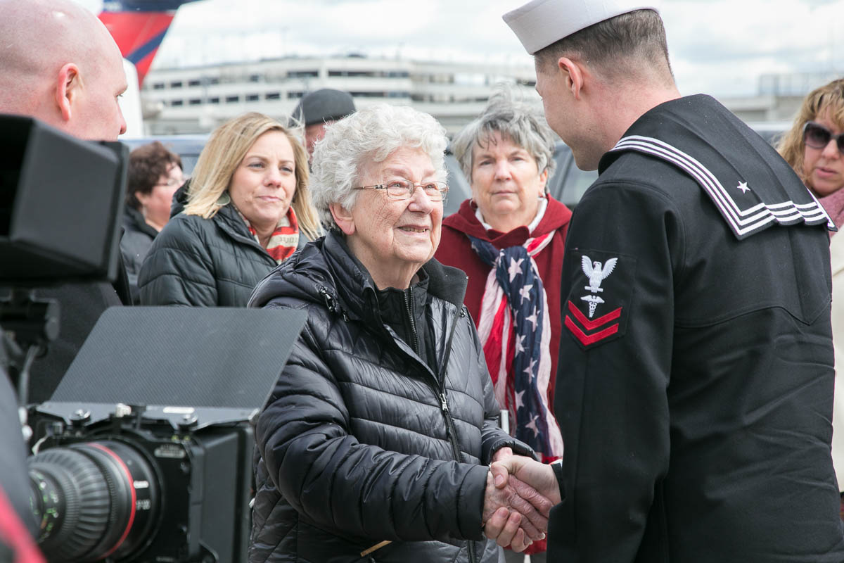 Joan Stough, sister of AOM2c Ora H. Sharninghouse shaking hands with navy officer